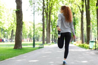 Genç bayan koşucu koşmadan önce ısınıyor.