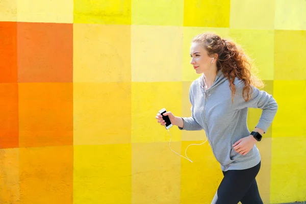 Vista lateral de la mujer corriendo contra la pared brillante — Foto de Stock