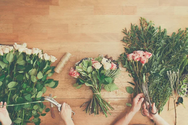 Çiçekçi ve asistanı olarak çiçek Dükkanı teslim gül buketi, tablo üstten görünüm olun