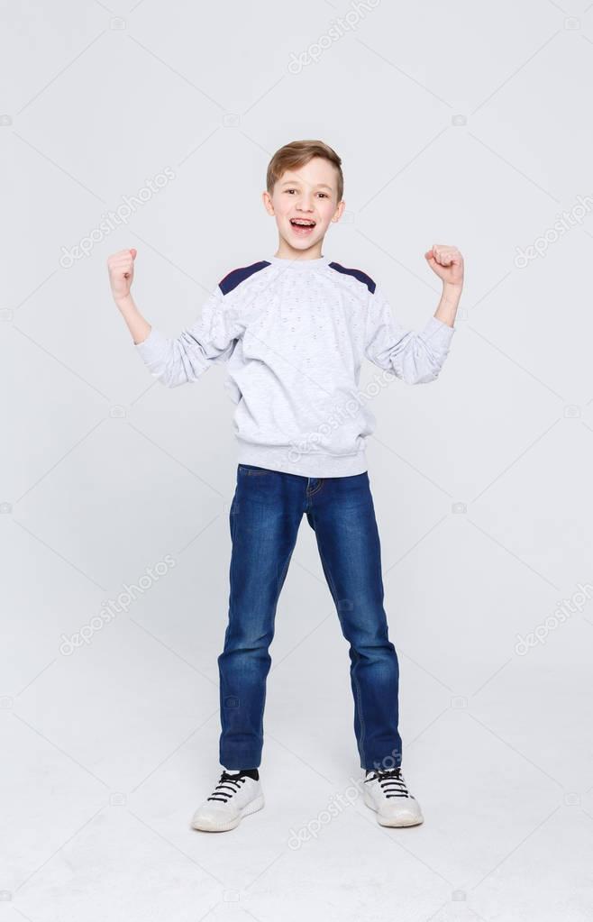Portrait of cheerful boy celebrating victory at studio background