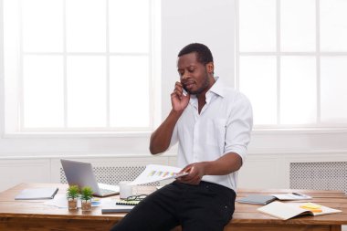 Genç işadamı okuma belgeleri siyah ve mobil modern beyaz ofisinde konuşmak