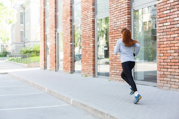 Young woman running in city back view