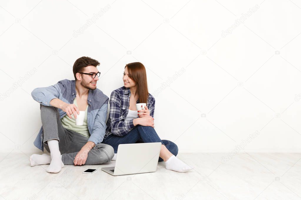 Casual couple discuss something sitting with laptop, studio shot