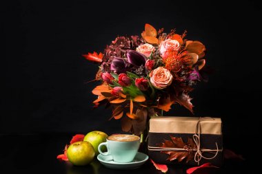 Siyah arka plan üzerine cappuccino kahve ve çiçek kompozisyon