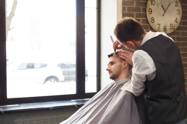 Homem recebendo corte de cabelo por cabeleireiro na barbearia — Fotografia de Stock