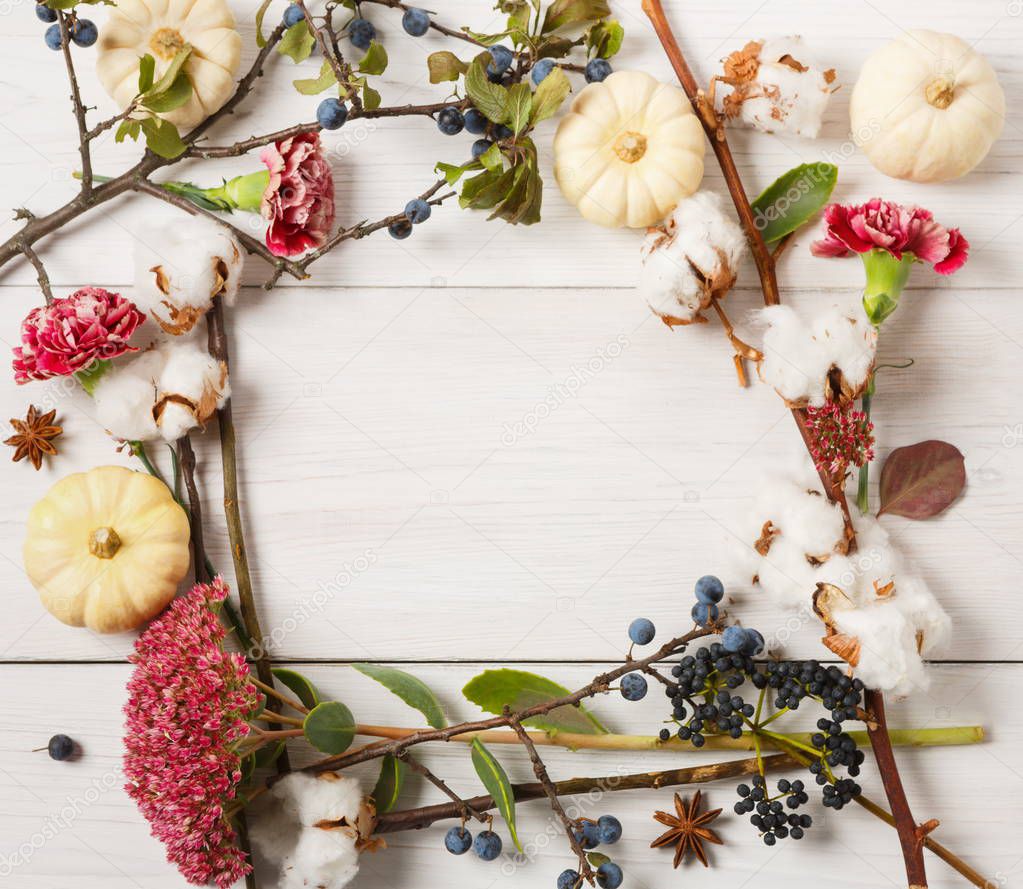 Autumn frame of dried flowers on white wood background
