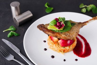 Restoran yemekleri. Ördek confit siyah arka plan üzerine sebzeli