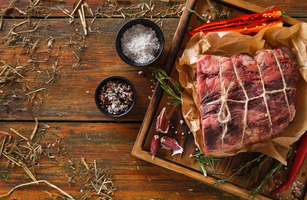 Raw aged prime black angus beef in craft papper on rustic wood — Stock Photo, Image