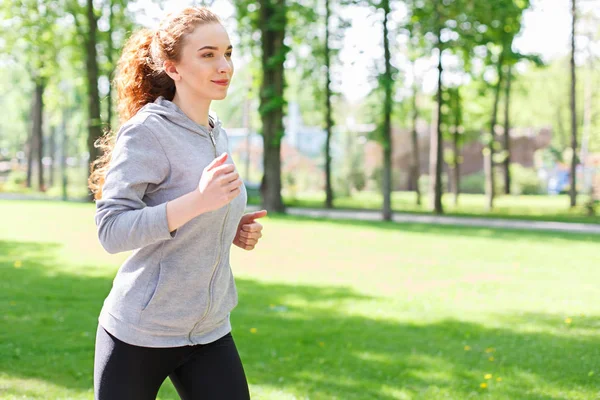 Mujer joven corriendo en el parque verde, espacio de copia — Foto de Stock