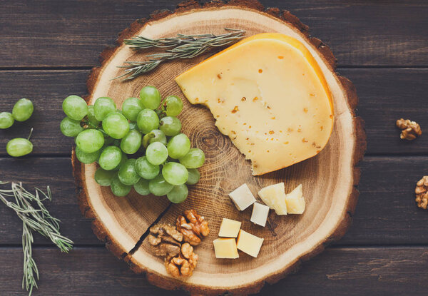 Cheese platter, gouda herb on natural wood disc with grapes and