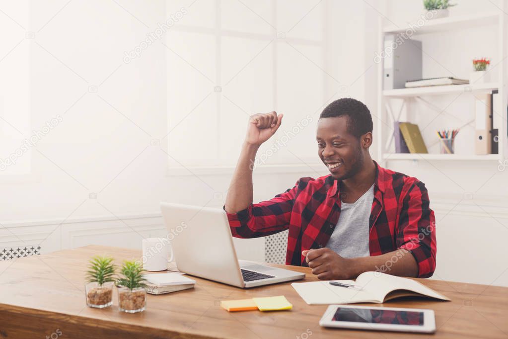 Happy black businessman in modern office, work with laptop
