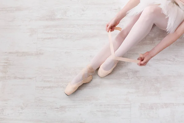 Bailarina se pone zapatos de ballet puntiagudos, piernas elegantes —  Fotos de Stock