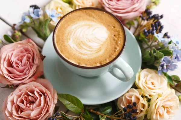 Cappuccino coffee and flowers composition on white wood