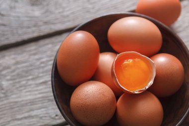 Ahşap arka plan üzerinde kase taze kahverengi yumurta