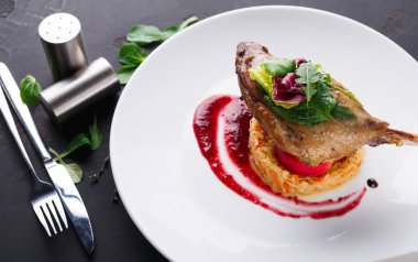 Restoran yemekleri. Ördek confit siyah arka plan üzerine sebzeli