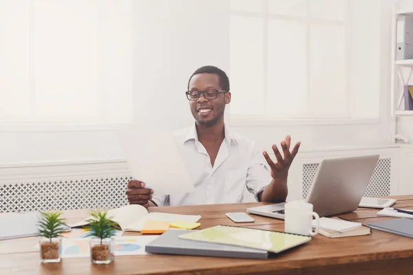 Young black businessman read documents in modern white office