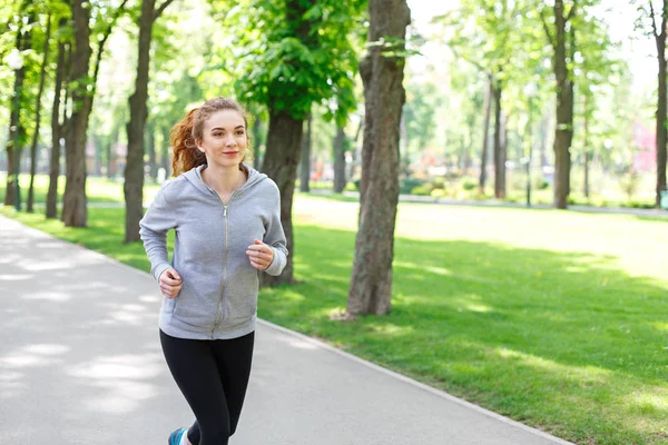Mujer joven corriendo en el parque verde, espacio para copiar —  Fotos de Stock