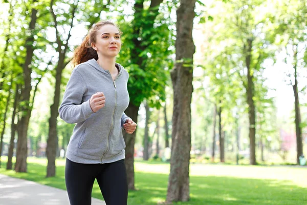 Mujer joven corriendo en el parque verde, espacio para copiar —  Fotos de Stock