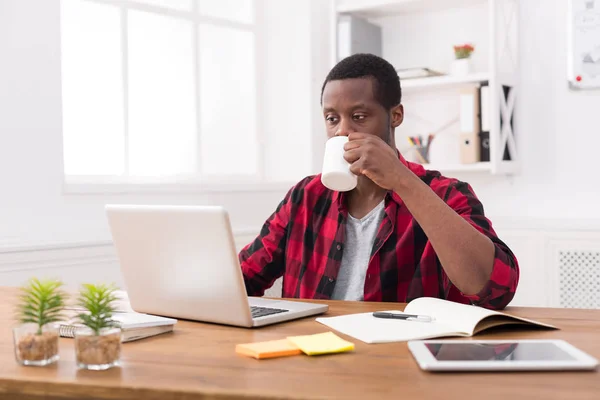 Uomo d'affari nero in ufficio casual, lavoro con il computer portatile e bere caffè — Foto Stock