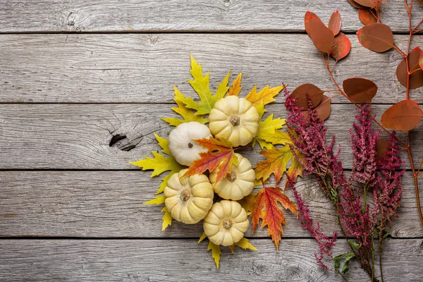 Herbst-Stillleben mit Kürbissen und trockenen Blättern auf Holzgrund — Stockfoto