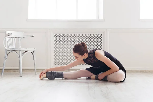 Klassischer Balletttänzer dehnt sich in weißem Trainingsanzug — Stockfoto