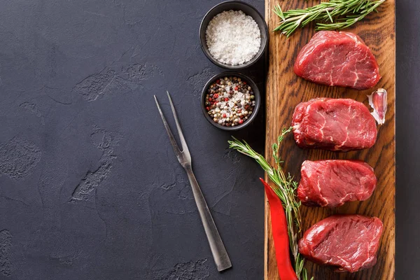 Filet mignon steaks et épices sur bois sur fond noir — Photo