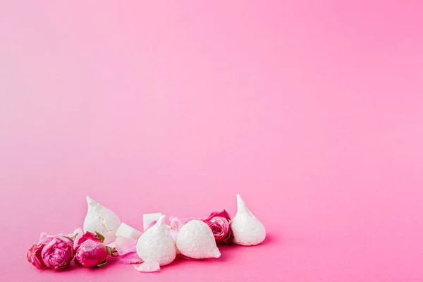Merengues brancos e botões de rosas no fundo rosa — Fotografia de Stock