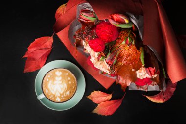 Siyah arka plan üzerine cappuccino kahve ve çiçek kompozisyon