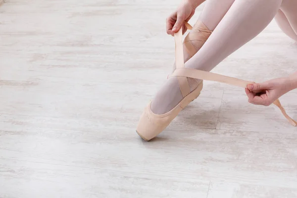 Bailarina coloca em sapatos de balé pointe, pernas graciosas — Fotografia de Stock