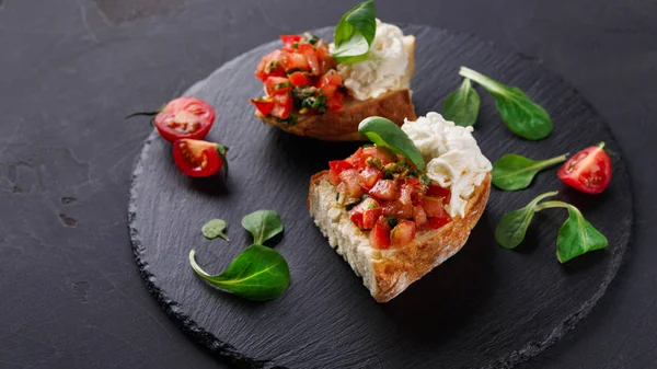 Bruschetta com queijo e legumes sobre fundo preto — Fotografia de Stock