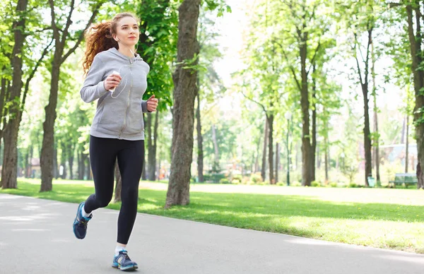 Young woman jogging in green park, copy space — Stock Photo, Image