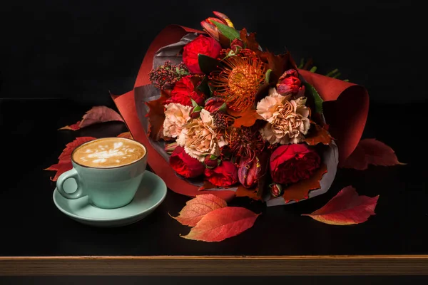 Cappuccino coffee and flowers composition on black background