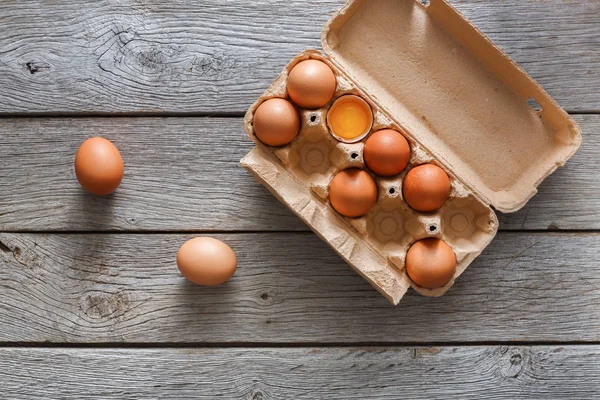 Fresh brown eggs in carton on rustic wood background