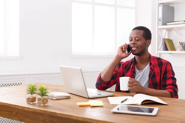 Joven hombre de negocios negro hablando en el móvil en la oficina blanca moderna —  Fotos de Stock