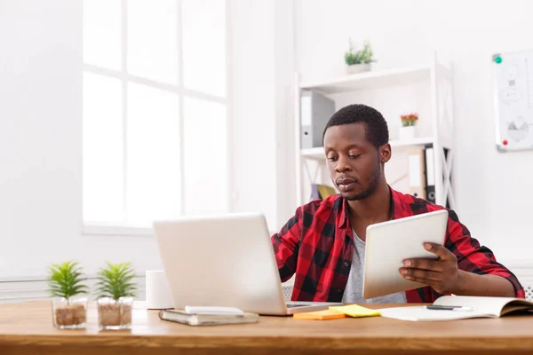 Серьезный молодой черный счастливый бизнесмен в офисе, работа с ноутбуком — стоковое фото