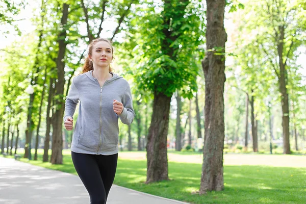 Mujer joven corriendo en el parque verde, espacio de copia —  Fotos de Stock