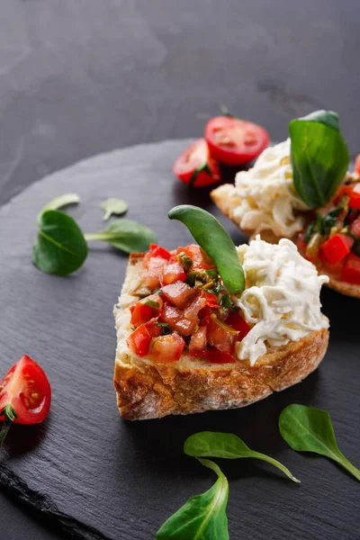 Bruschetta com queijo e legumes sobre fundo preto — Fotografia de Stock