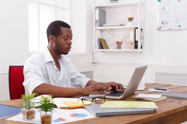 Genç siyah işadamı modern beyaz ofis içinde laptop ile çalışma