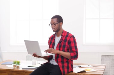 Dalgın siyah işadamı rahat ofiste dizüstü bilgisayar ile çalışmak