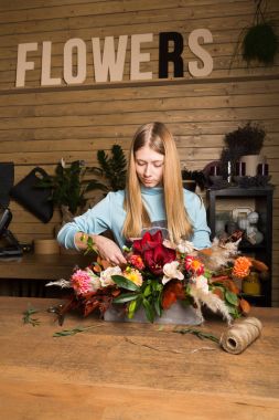 Genç kadın renkli sonbahar buket çiçek dükkanında oluşturma