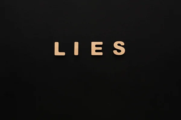 Palavra mentiras sobre fundo preto — Fotografia de Stock