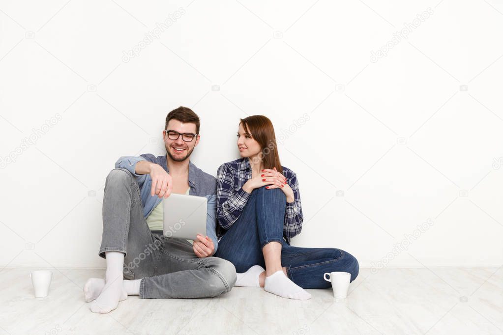Smiling couple web-surfing on tablet, studio shot