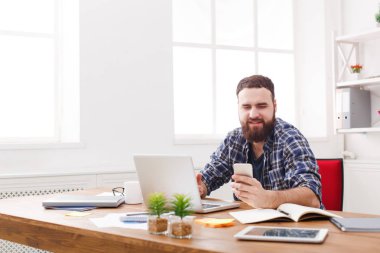 Genç işadamı tarafından dizüstü bilgisayar cep telefonu kullanarak Office gülümsedi