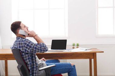 Konsantre genç işadamı modern beyaz ofiste bir telefon konuşma vardır