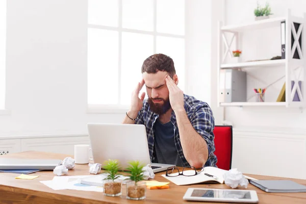 Young benadrukt zakenman met laptop in moderne witte kantoor — Stockfoto