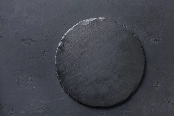 Порожня сільська чорна сланцева кам'яна тарілка на темному фоні — стокове фото