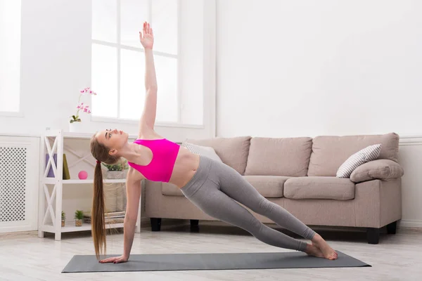 Mujer entrenando yoga en pose de tablón lateral . —  Fotos de Stock