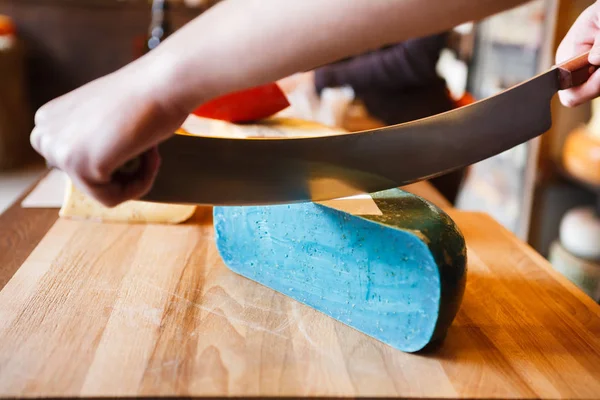 Cutting gouda pesto blue cheese in grocery shop — Stock Photo, Image