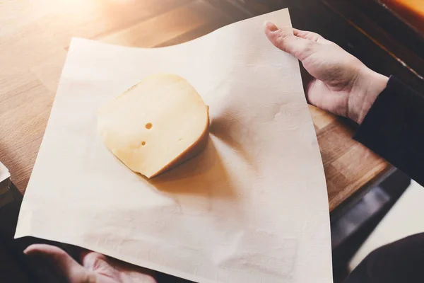 Помощница продавщицы упаковывает кусок сыра — стоковое фото