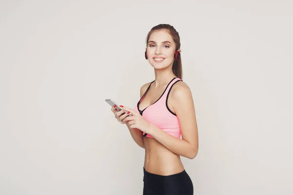 Fitness lány fejhallgató válassza a zene a telefonon — Stock Fotó